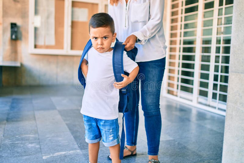 Adorable estudiante latino y mamá esperando en la escuela fotografía de archivo