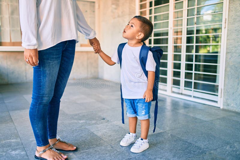 Adorable estudiante latino y mamá esperando en la escuela imagen de archivo libre de regalías