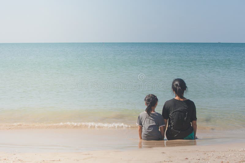 Woman and children sitting back to back on sand beach and looking to seascape. royalty free stock image Woman and children sitting back to back on sand beach and looking to seascape. royalty free stock image