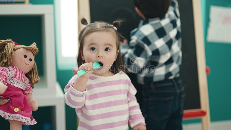 Adorable garçon et fille de l'école maternelle dessin sur le tableau suçant un jouet de fourche à la maternelle