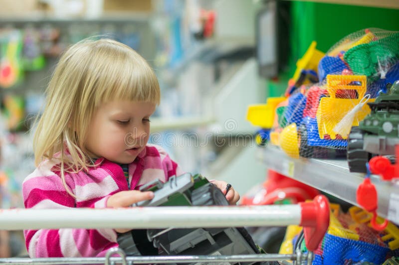 Adorable girl look to toys sit in shopping cart