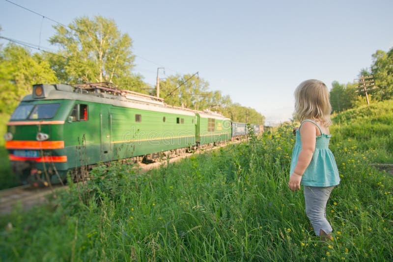 Adorable girl stay on hill and look to train