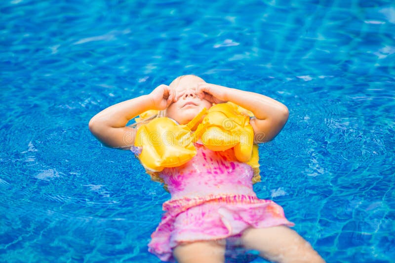 Adorable girl with yellow life vest in pool in tropical beach re