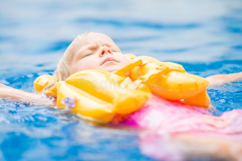 Adorable girl with yellow life vest in pool in tropical beach re