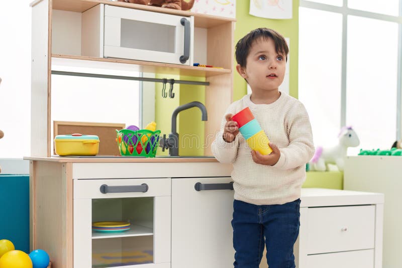Adorable Hispanic Boy Playing with Play Kitchen Standing at