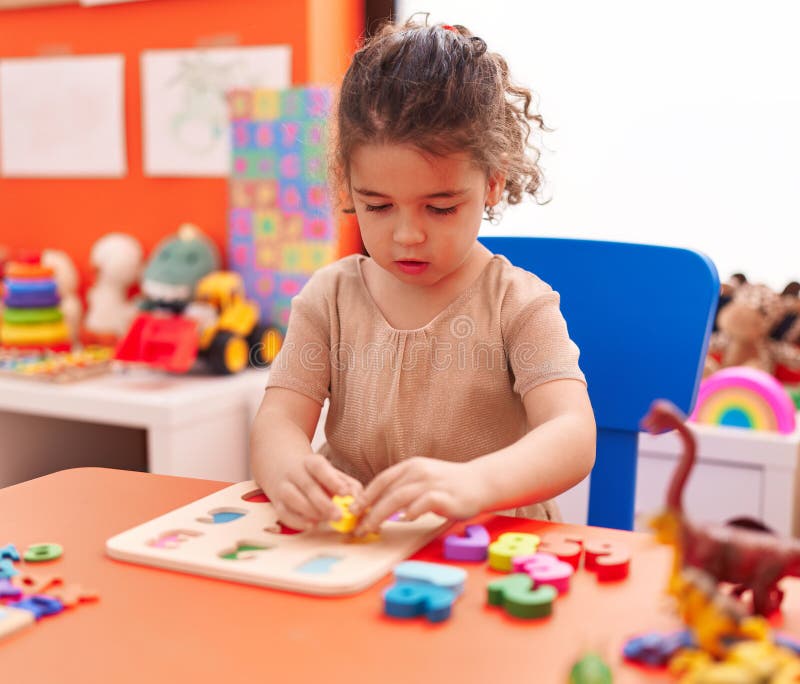 Adorable Hispanic Girl Playing with Maths Puzzle Game Sitting on Table