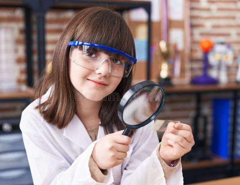 Adorable Hispanic Girl Student Looking Sample Using Magnifying Glass at Laboratory Classroom