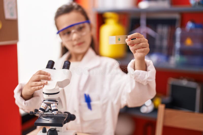 Adorable hispanic girl student using microscope looking sample at classroom royalty free stock images