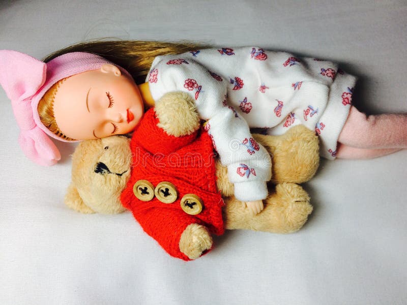 An adorable Japanese doll is sleeping with her teddy bear. royalty free stock photos An adorable Japanese doll is sleeping with her teddy bear. royalty free stock photos