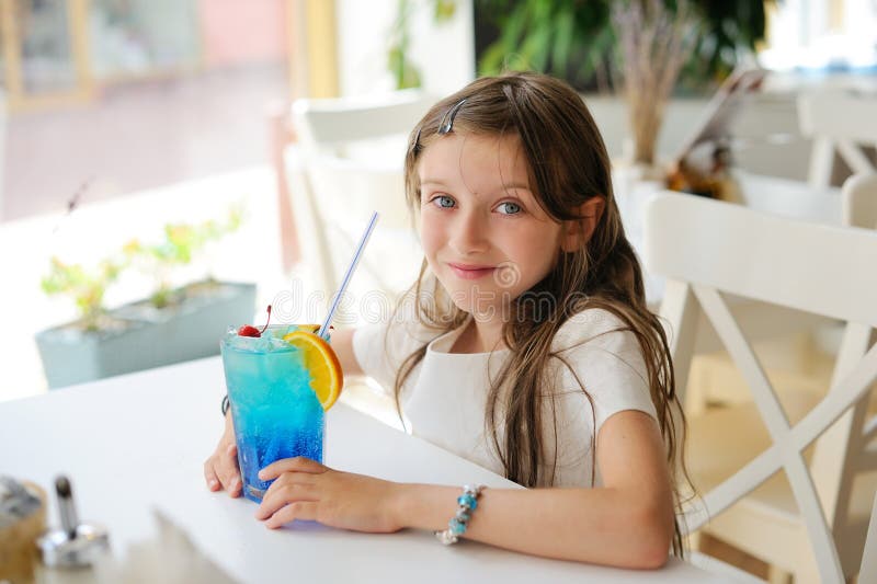 Adorable kid girl in cafe with coctail