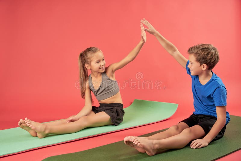 Adorable Kids Sitting on Yoga Mats and Giving High Five Stock