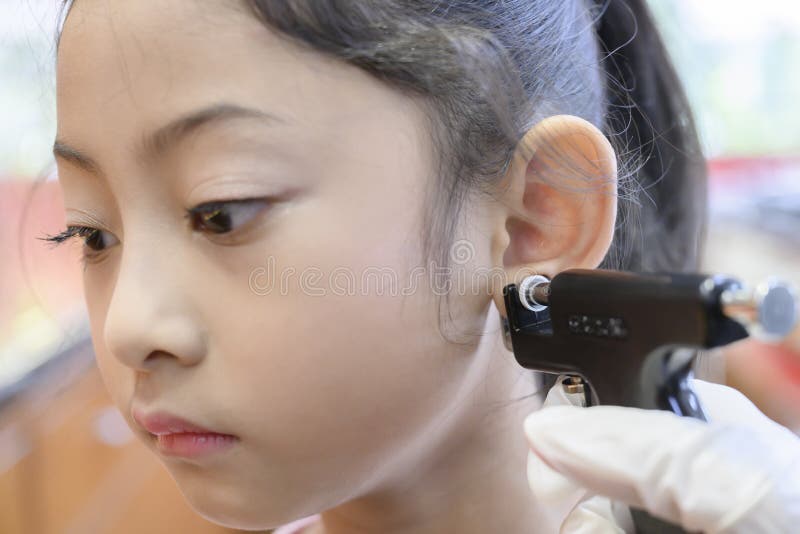 Adorable Little Asian Girl Having Ear Piercing Process. Stock Image