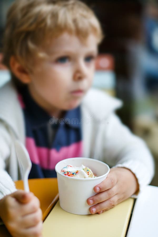 Adorable Little Boy Eating Frozen Yoghurt Ice Cream in Cafe Stock Image