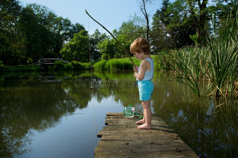 Adorable Little Boy Fishing from Wooden Dock on a Lake on Sunny Day