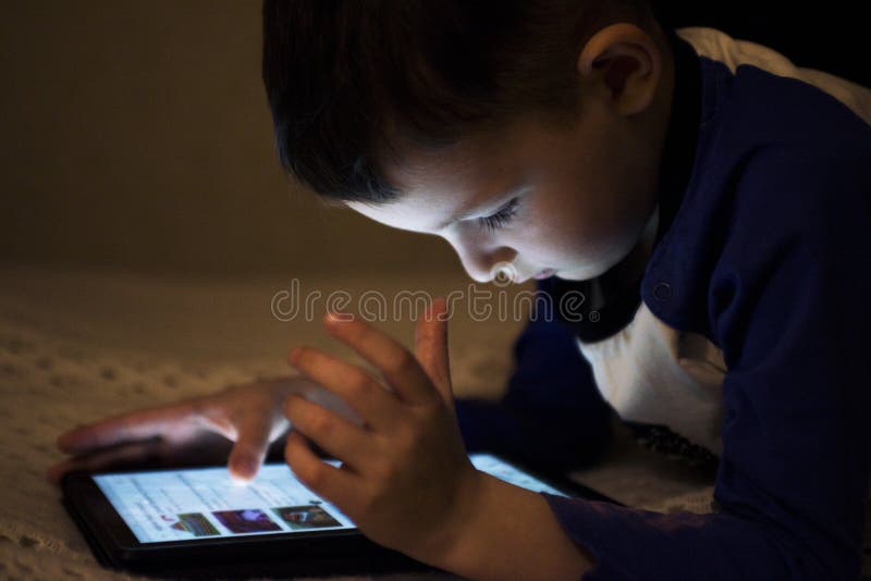 Adorable little boy playing on a digital tablet. Boy looking at digital tablet. Parental permission concepts, safety online