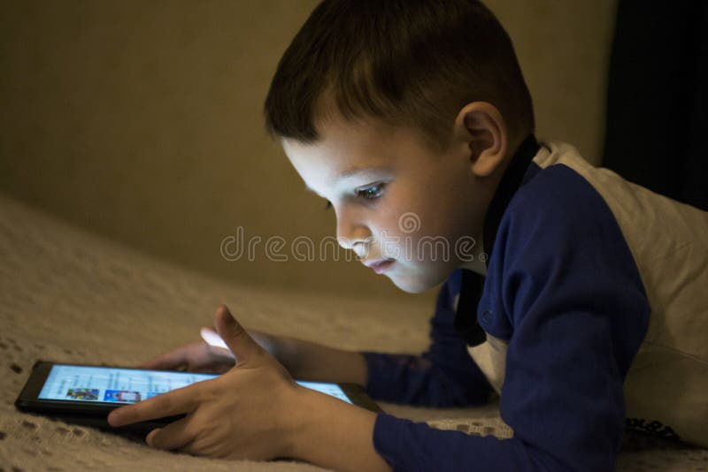 Adorable little boy playing on a digital tablet. Boy looking at digital tablet. Parental permission concepts, safety online