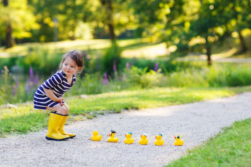 Adorable little child of 2 playing with yellow rubber ducks in s