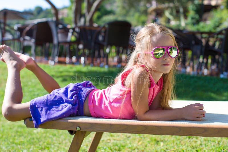 Adorable little girl on beach lounger outdoors