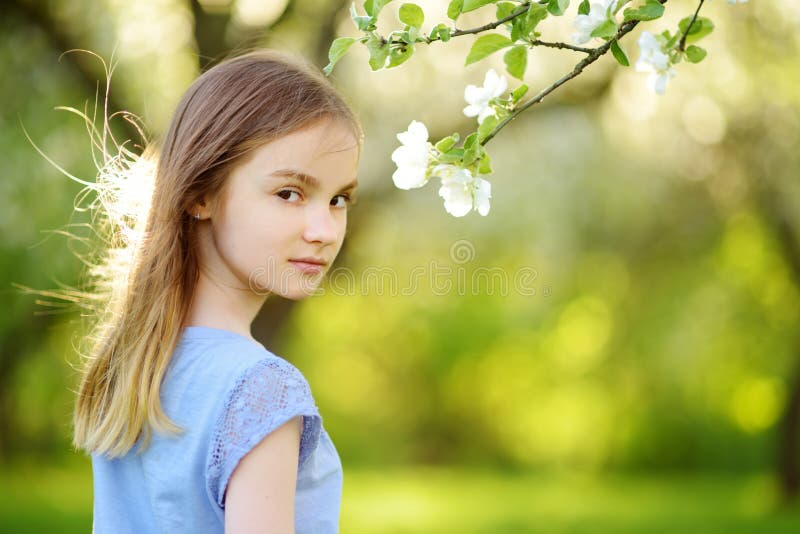 Adorable little girl in blooming apple tree garden on beautiful spring day