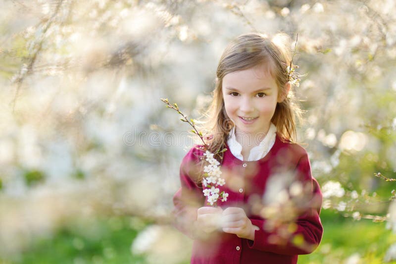 Adorable little girl in blooming cherry garden