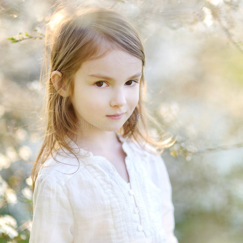 Adorable little girl in blooming cherry garden