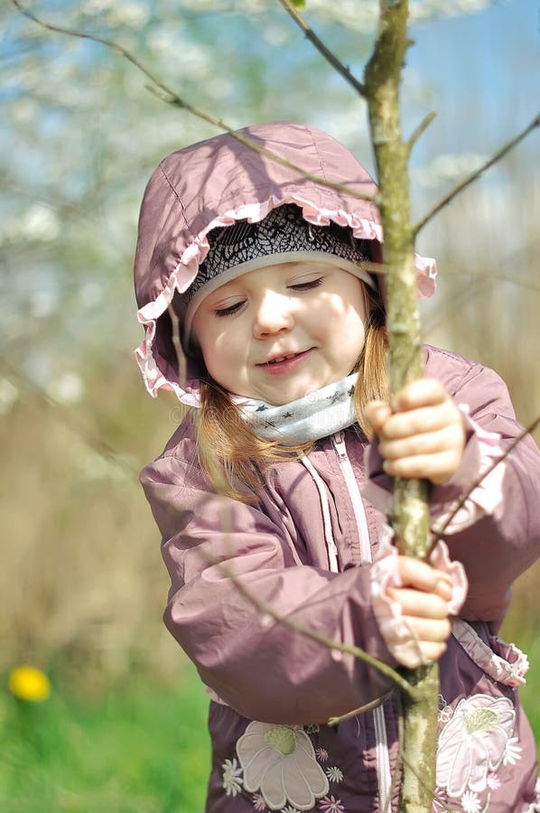 Adorable little girl in blooming cherry garden on beautiful spring day