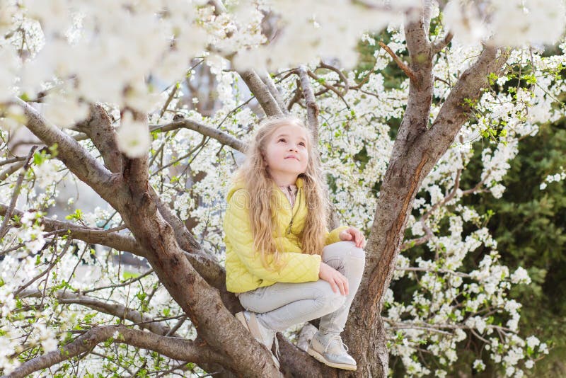 Adorable little girl in blooming cherry tree garden on beautiful spring day