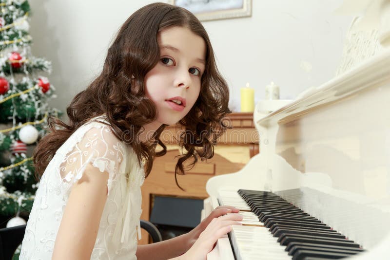 Beautiful girl in a white dress sitting at the piano. royalty free stock photography Beautiful girl in a white dress sitting at the piano. royalty free stock photography