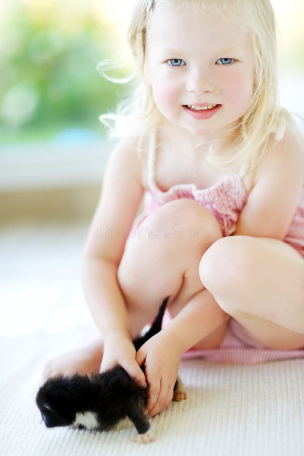 Adorable little girl playing with small kitten