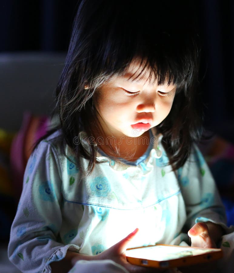Adorable little girl playing smartphone lying on a bed stock images Adorable little girl playing smartphone lying on a bed stock images