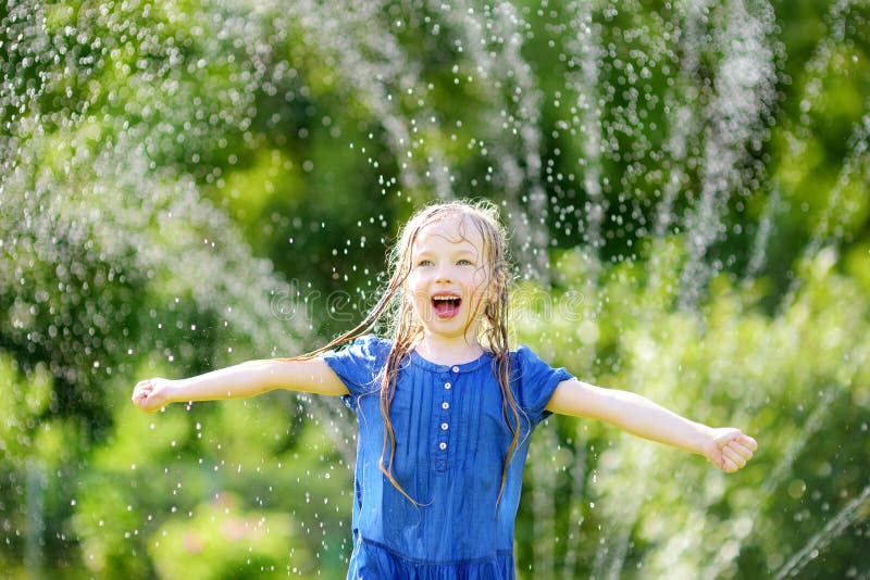 Adorable Little Girl Playing With A Sprinkler In A 