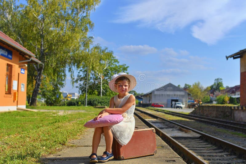 Adorable little girl on a railway station, waiting for the train with vintage suitcase. Traveling, holiday and chilhood royalty free stock image Adorable little girl on a railway station, waiting for the train with vintage suitcase. Traveling, holiday and chilhood royalty free stock image