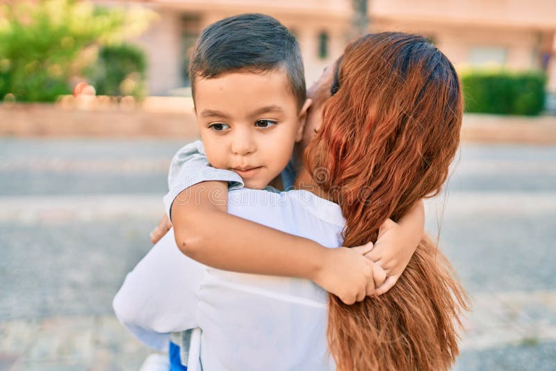 Adorable madre latina e hijo sonriendo alegre abrazo en la ciudad fotografía de archivo