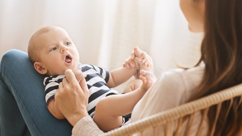 Adorable newborn baby cooing while lying on mother`s lap