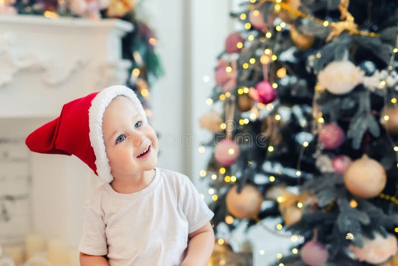 Adorable niño lindo divirtiéndose jugando en casa con sombrero rojo santa claus y árbol de Navidad festivo en segundo plano Niño fotografía de archivo Adorable niño lindo divirtiéndose jugando en casa con sombrero rojo santa claus y árbol de Navidad festivo en segundo plano Niño fotografía de archivo