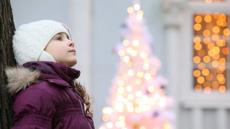 Adorable petite fille debout près d'un arbre devant banque de vidéos