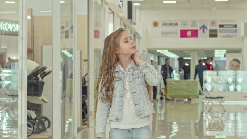 Adorable petite fille portant joyeusement un sac de shopping en flânant dans le centre commercial banque de vidéos