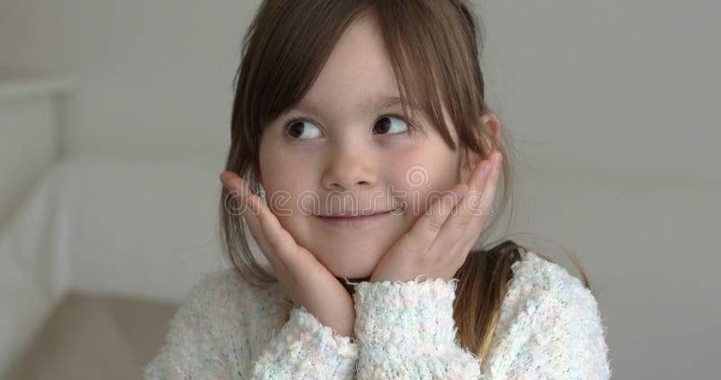 Adorable petite fille regardant la caméra avec des mains sur les joues Sourire banque de vidéos