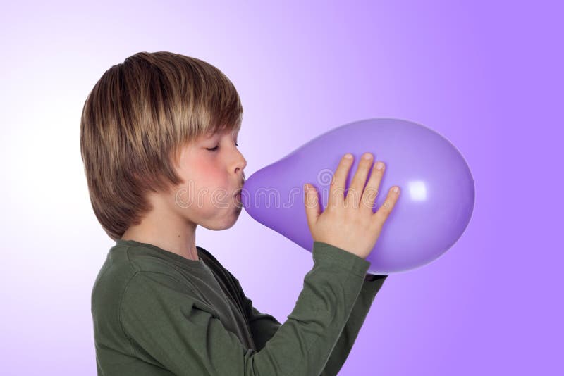 Adorable preteen boy blowing up a purple balloon