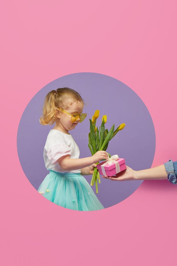 Adorable smiling child with spring flower bouquet and greating card in circle hole in the wall. Little toddler girl holding yellow