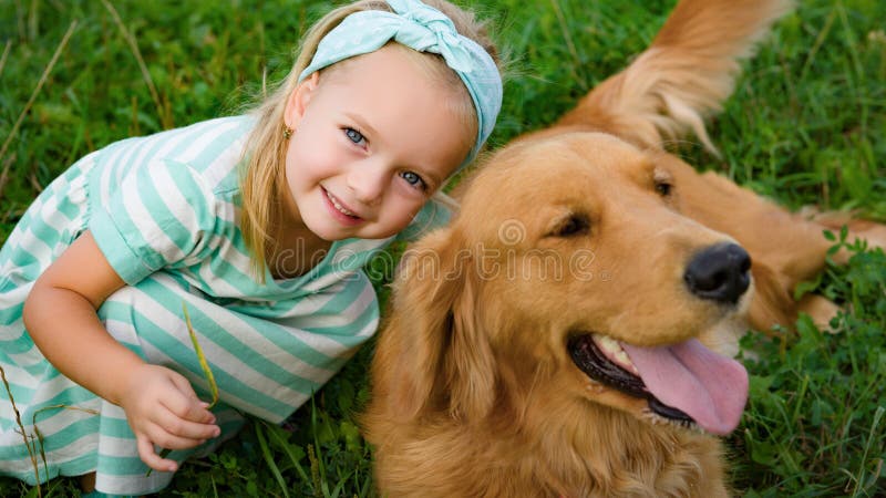 Adorable smiling little blond girl playing with her cute pet dog