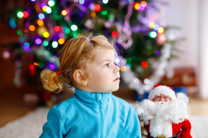 Adorable toddler girl playing with gifts and Christmas Santa Claus toys. Little child having fun with decorated and stock images Adorable toddler girl playing with gifts and Christmas Santa Claus toys. Little child having fun with decorated and stock images
