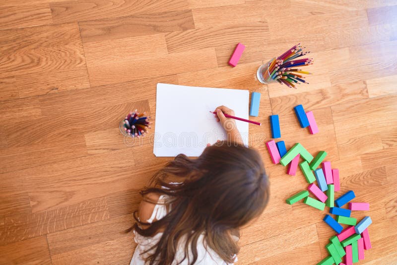 Adorable Toddler Lying Down on the Floor Drawing Using Paper and