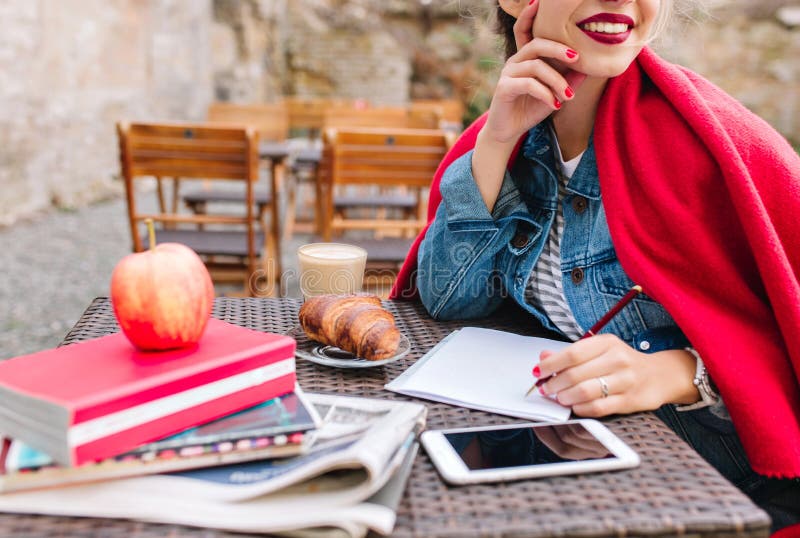 Adorable young woman is waiting for the inspiration to draw a picture. Charming girl makes notes in a notebook during