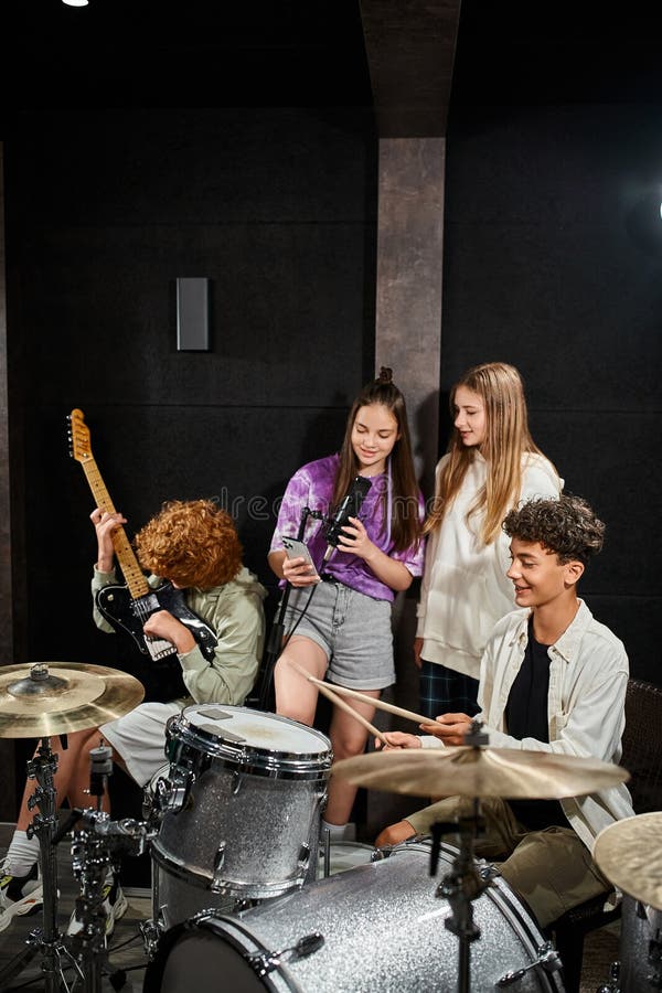 adorable teenage boys playing instruments while girls singing and looking at phone, musical group, stock photo. adorable teenage boys playing instruments while girls singing and looking at phone, musical group, stock photo