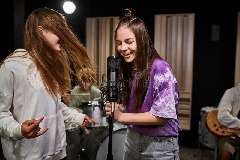 adorable jolly teenage girls singing and showing rock sign while boys playing various instruments, stock photo. adorable jolly teenage girls singing and showing rock sign while boys playing various instruments, stock photo