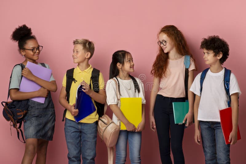 Adoráveis alunos de diferentes raças e idades a olhar uns para os outros sobre o fundo do palco imagem de stock Adoráveis alunos de diferentes raças e idades a olhar uns para os outros sobre o fundo do palco imagem de stock
