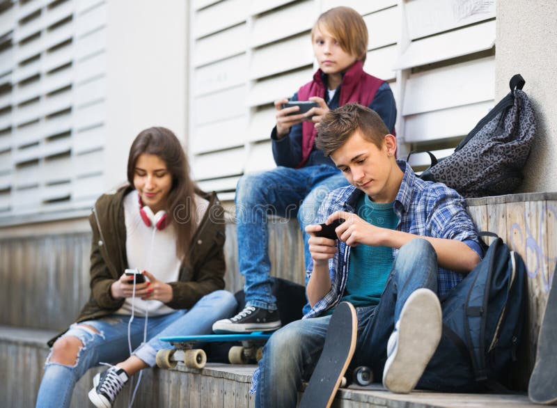 Ados heureux jouant sur des smarthphones et écoutant la musique photos libres de droits Ados heureux jouant sur des smarthphones et écoutant la musique photos libres de droits