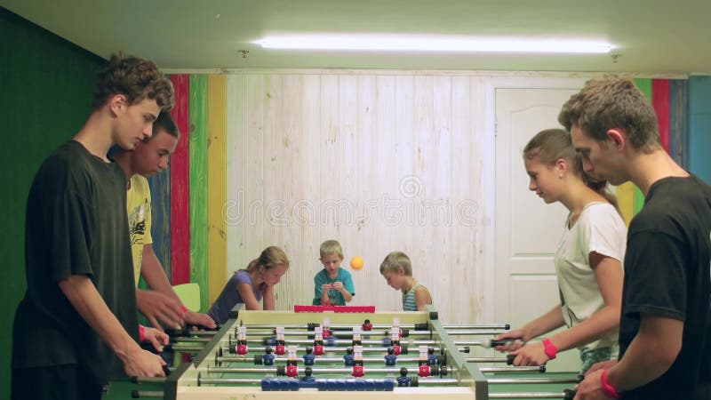 Ados jouant le football de table à l'intérieur, travail d'équipe en jeu de société, groupe du football de table de jeu d'enfants