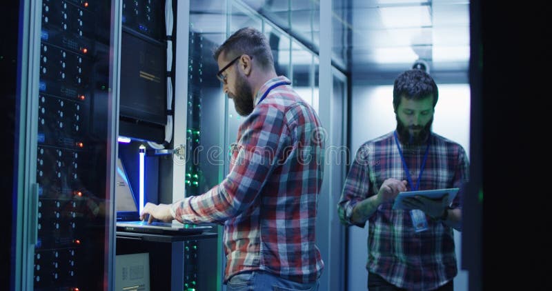 Bearded IT specialist setting servers in data center stock photography